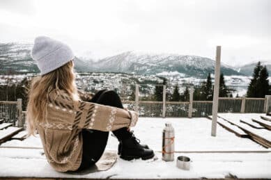 Kvinne nyter utsikten mot fjord og snødekte fjell