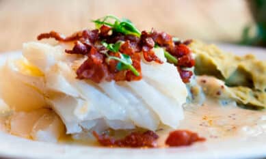Tradisjonell lutefisk servert med sprøstekt bacon, poteter og tilbehør.